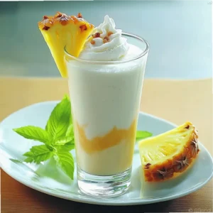 Pineapple rum-raisin milkshake in a tall glass garnished with a pineapple slice.