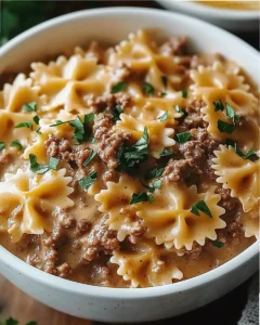 Creamy bowtie pasta with ground beef and cheddar cheese in a skillet