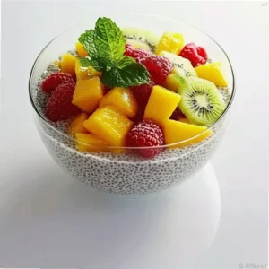 Glass bowl of chia seed fruit pudding topped with diced mango and kiwi, garnished with mint leaves
