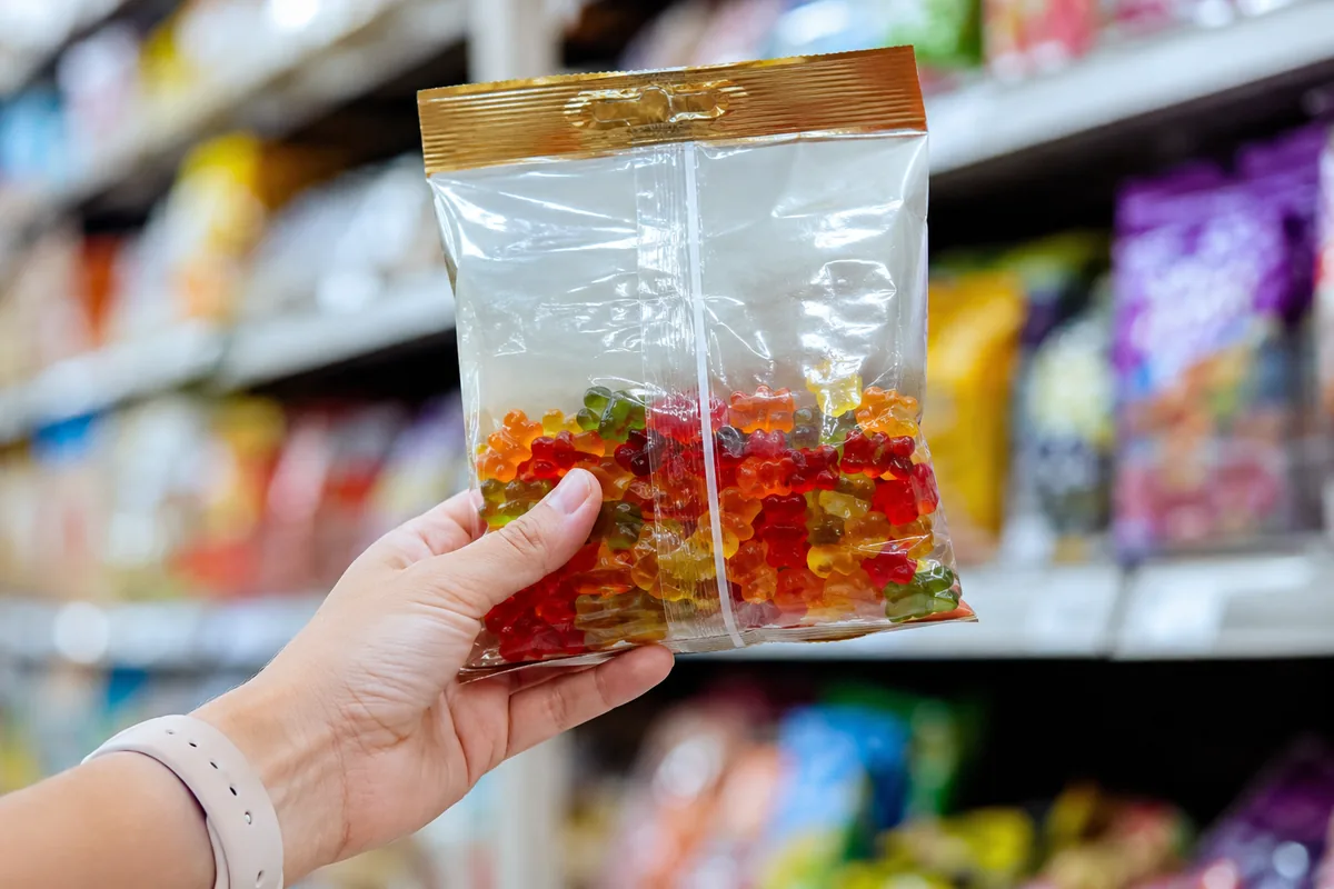 A hand holding a bag of gummy bears up to check the allergen panel